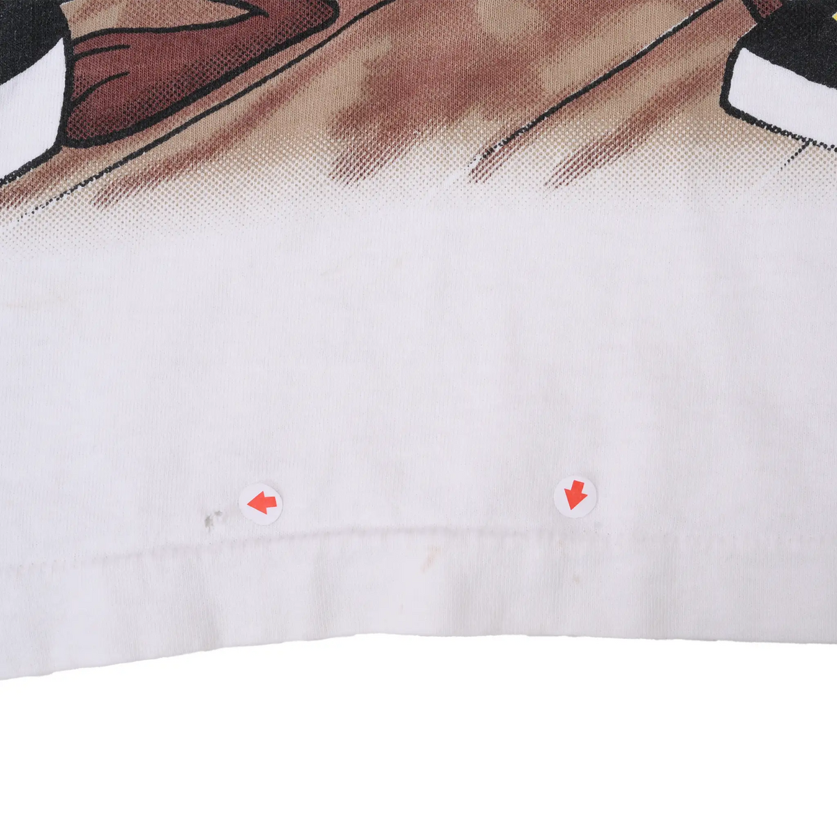 Close-up of white front hem with arrows marking two faint spots below the graphic