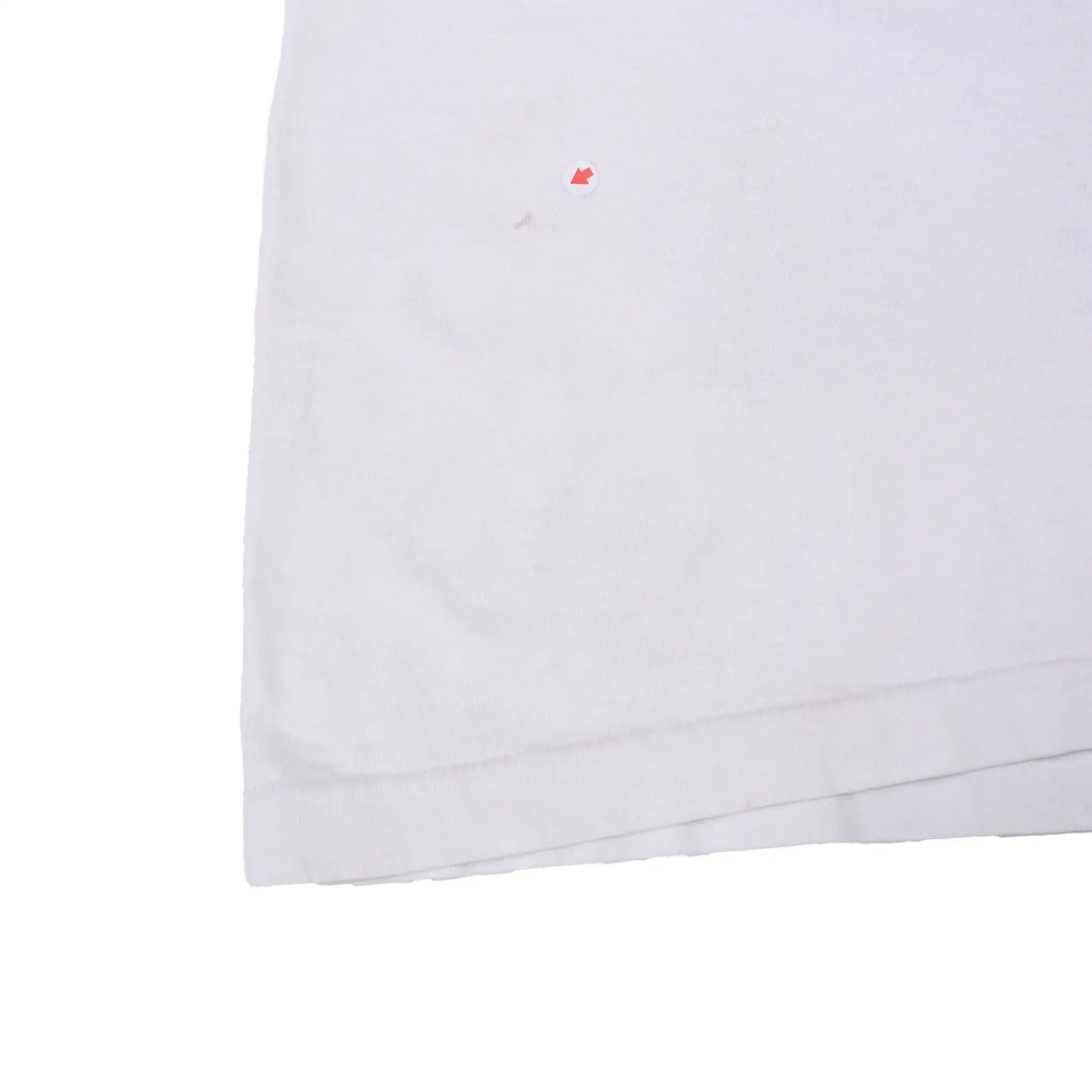 Close-up of lower back and hem with arrow marking a small spot on white fabric