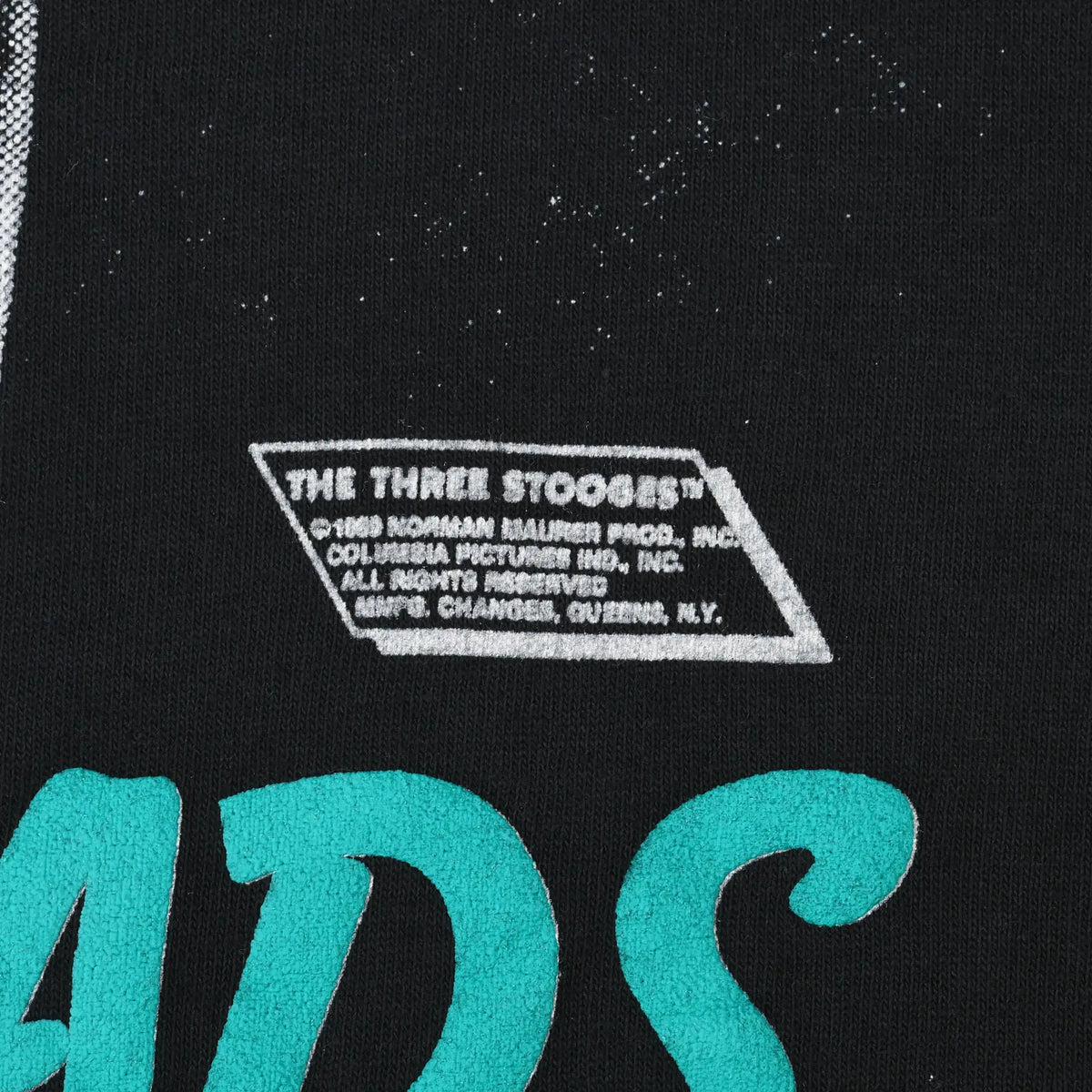 Close-up of The Three Stooges copyright print beside turquoise graphic lettering