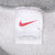 Close-up of white Nike neck tag with red Swoosh inside gray sweatshirt
