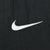 Close-up of white Nike Swoosh embroidery on black fabric