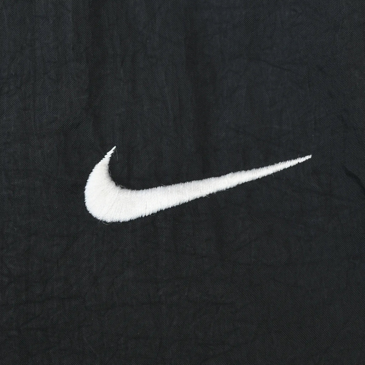 Close-up of white Nike Swoosh embroidery on black fabric