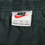 Nike waist label with red Swoosh and large size marking inside dark green track pants