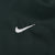 Close-up of white Nike Swoosh embroidery on dark green fabric