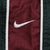 Close-up of white Nike Swoosh embroidery on burgundy side panel with white piping