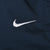 Close-up of white embroidered Nike Swoosh on blue track pants