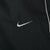 Close-up of white Nike Swoosh embroidery and piping on black track pants