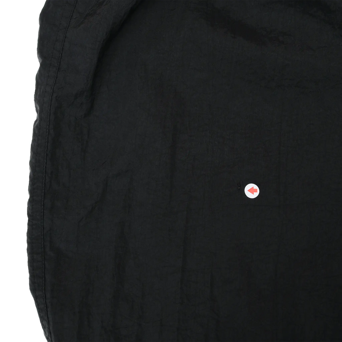 Close-up of black pant fabric with arrow marking a small spot