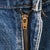 Close-up of brass Levi's zipper fly and orange stitching on blue denim