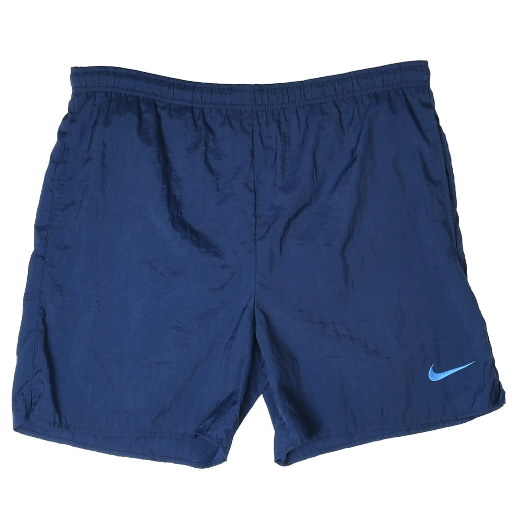 Front of navy blue Nike swim trunks with elastic waist and small light blue embroidered Swoosh