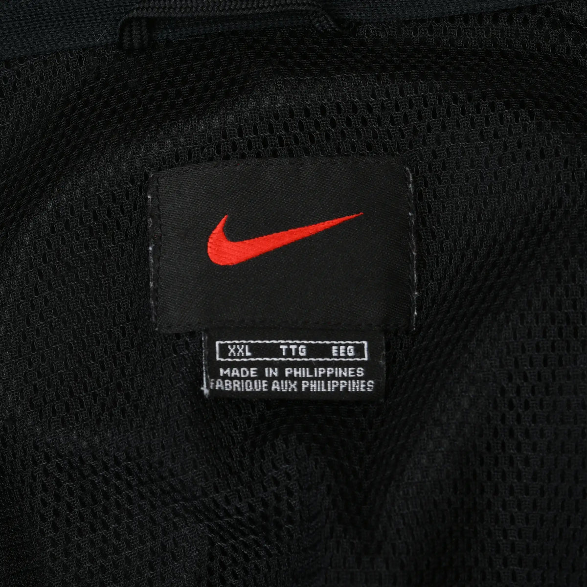 Nike neck label with red Swoosh and XXL size marking on black mesh lining