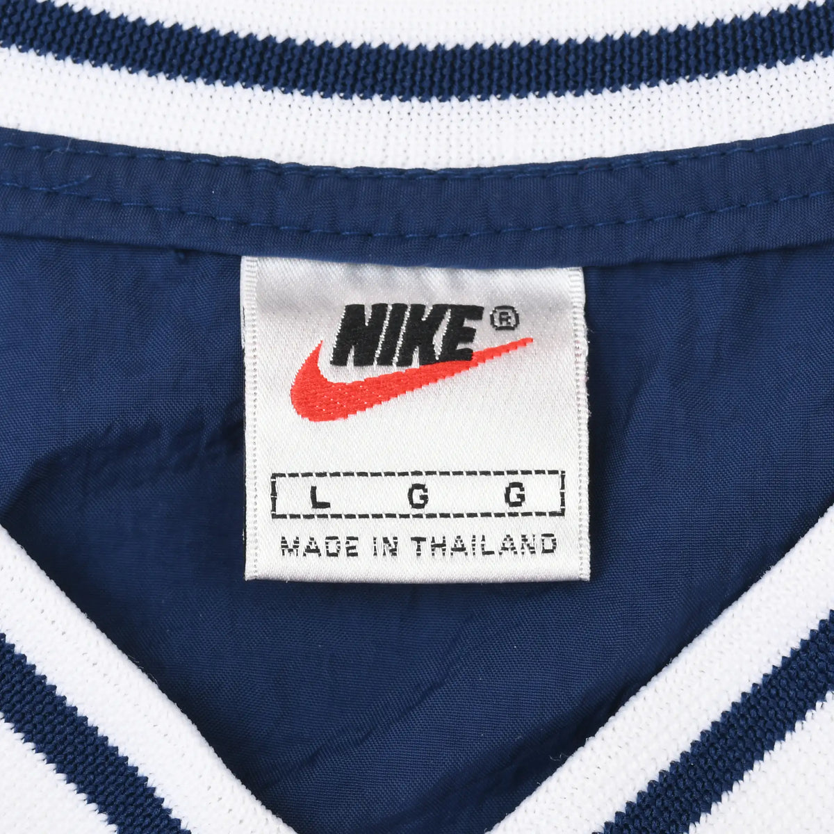 Close-up of Nike neck label inside navy pullover windbreaker with striped V-neck trim