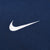 Close-up of white Nike Swoosh embroidery on navy windbreaker fabric