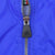 Close-up of adidas-branded black zipper pull and metal zipper on royal blue fabric