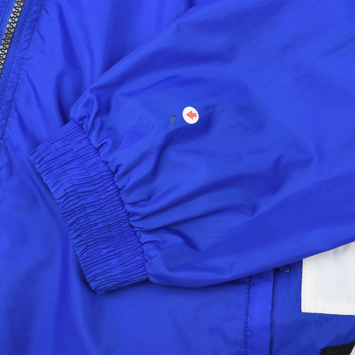 Close-up of royal blue elastic sleeve cuff with a small mark indicated near the seam