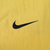 Close-up of black embroidered Nike Swoosh on yellow jacket fabric