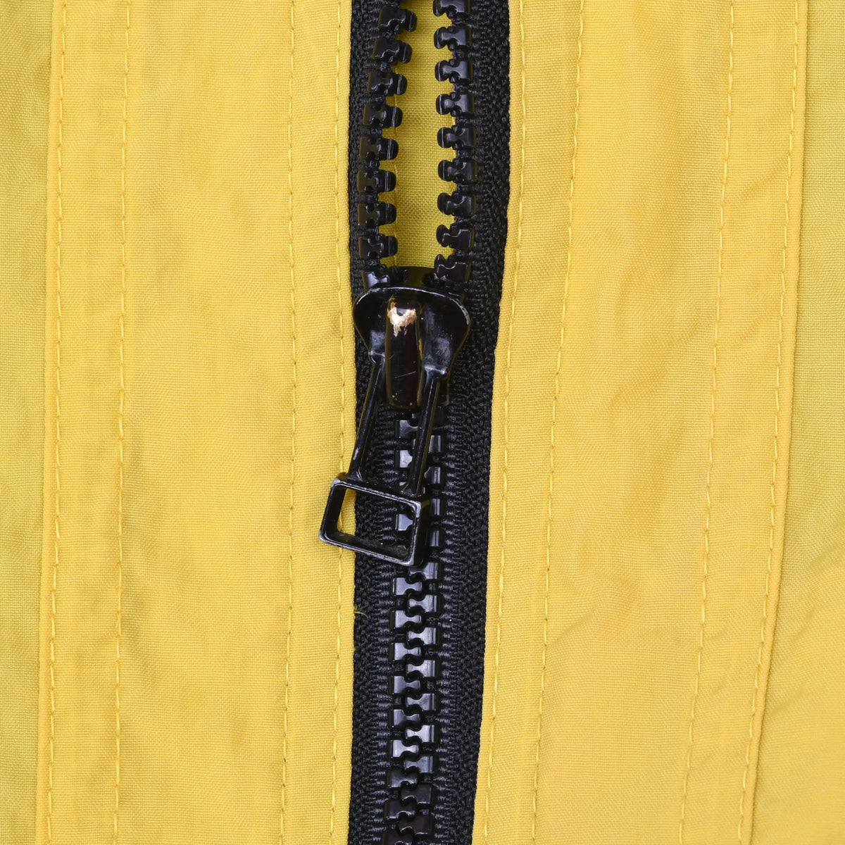Close-up of black front zipper and pull on yellow Nike windbreaker