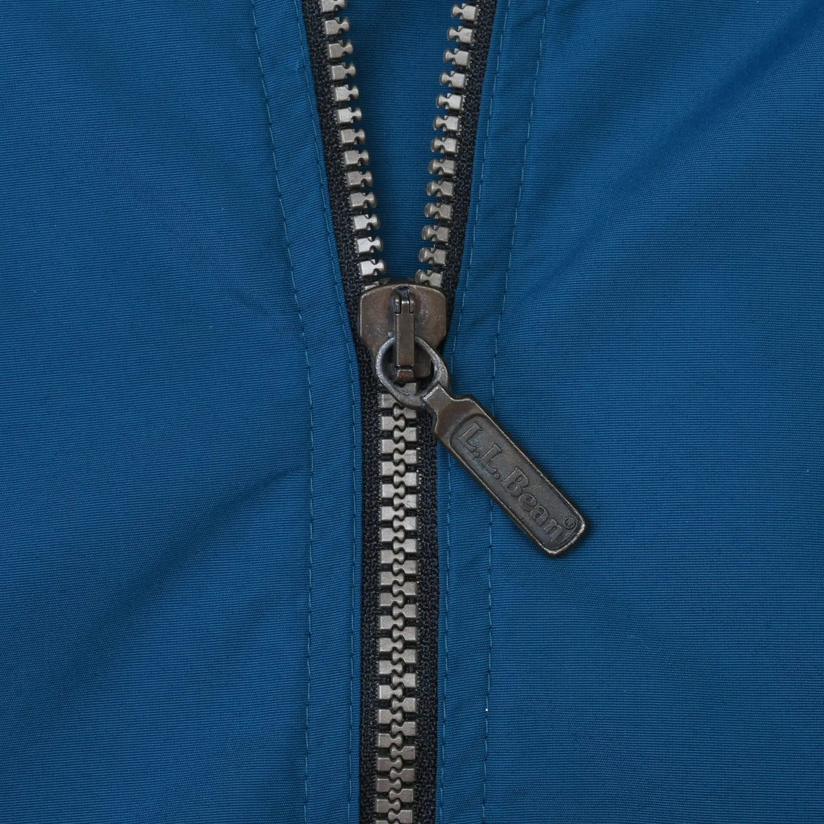 Close-up of metal L.L.Bean zipper pull on teal fabric