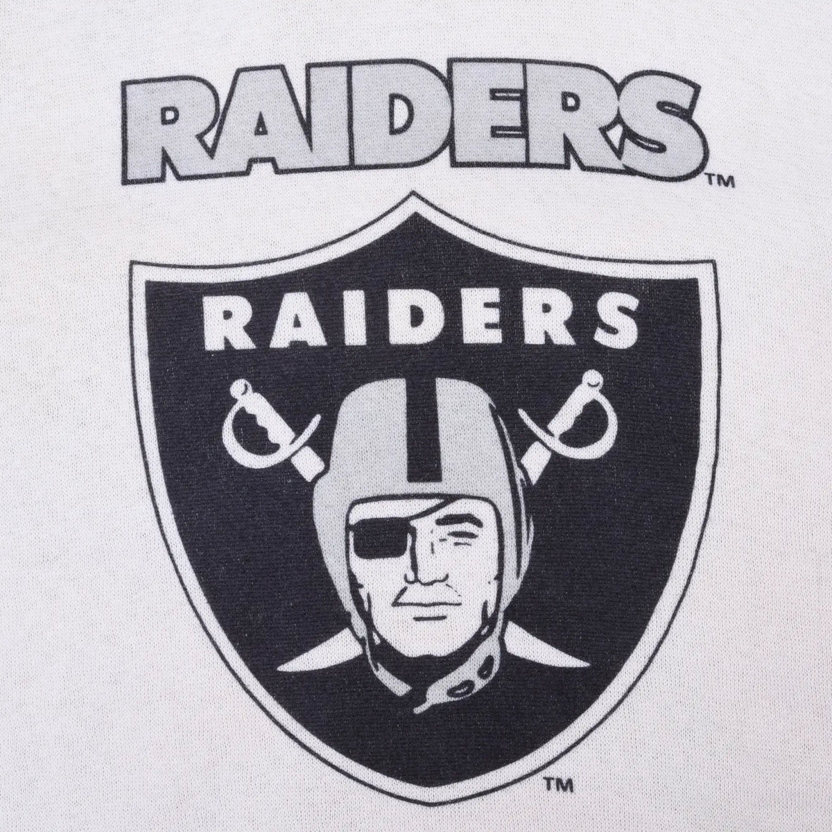 Close-up of black Raiders wordmark and shield print on silver sweatshirt fabric