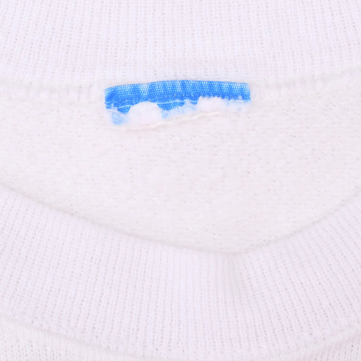 Close-up of white sweatshirt collar and partially removed blue neck label