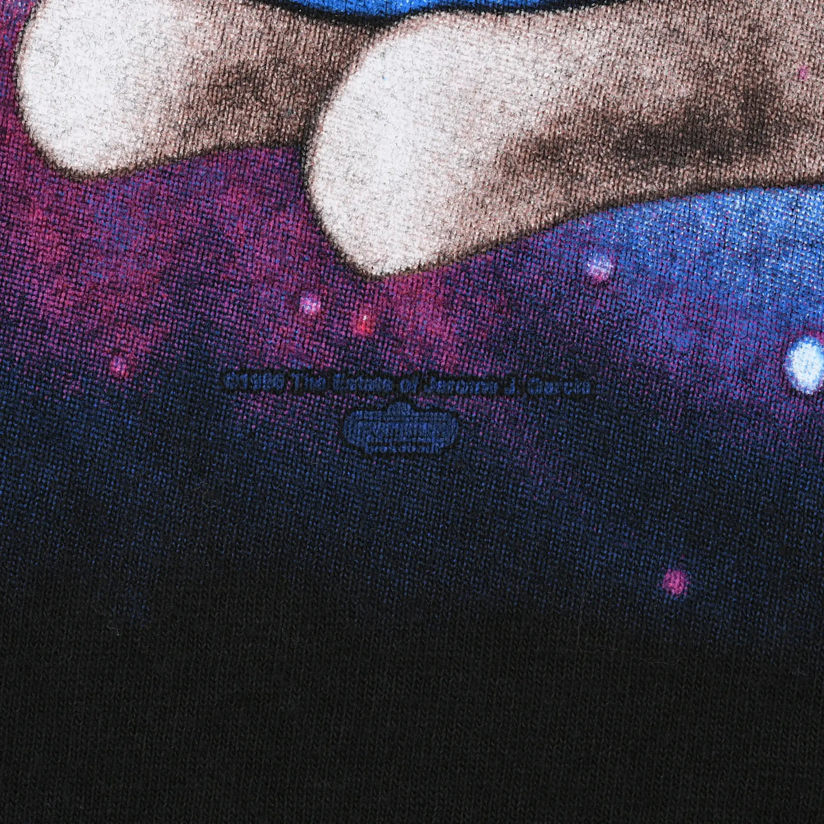 Close-up of faint copyright text beneath the front graphic on black fabric