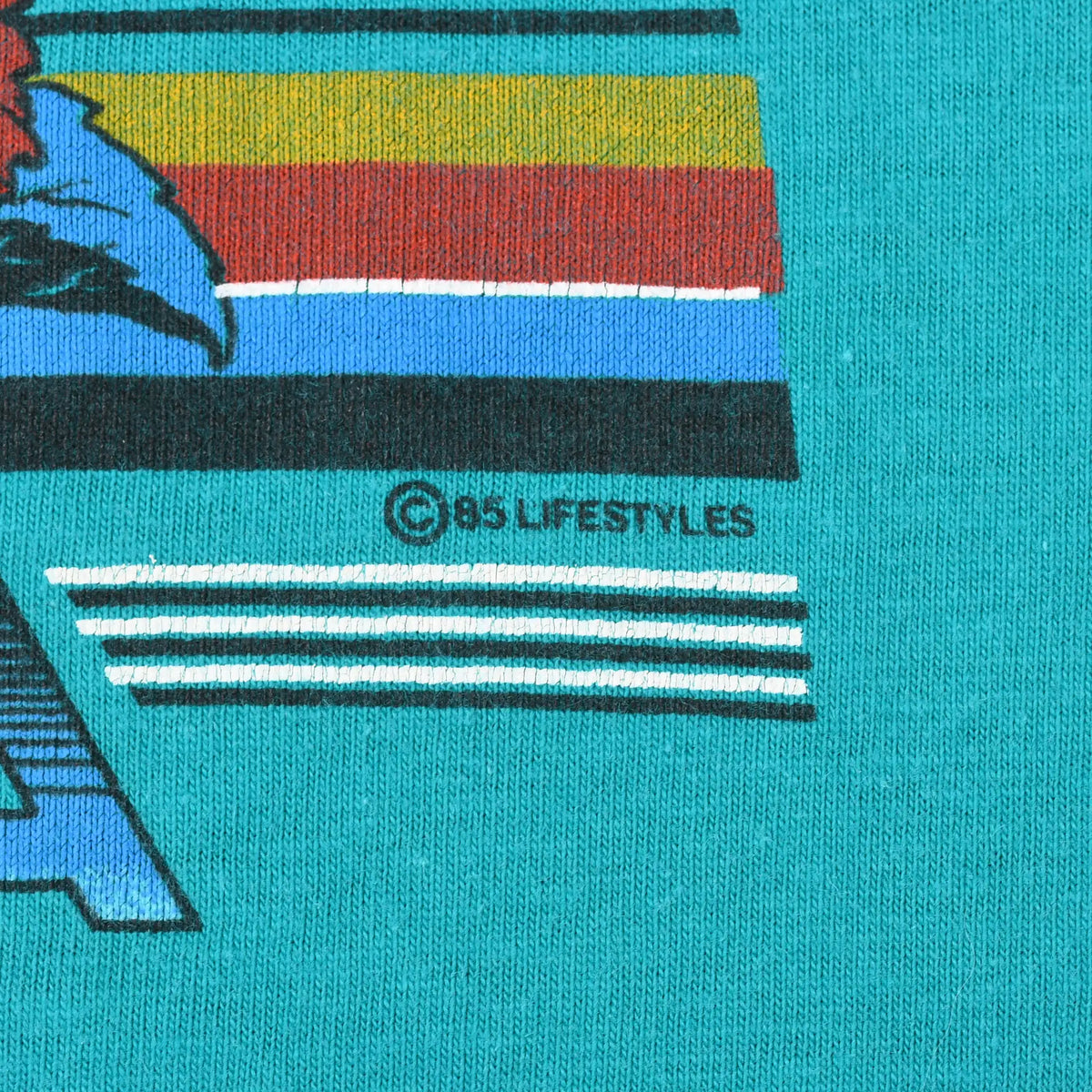 Close-up of striped print detail and ©85 Lifestyles mark on teal fabric