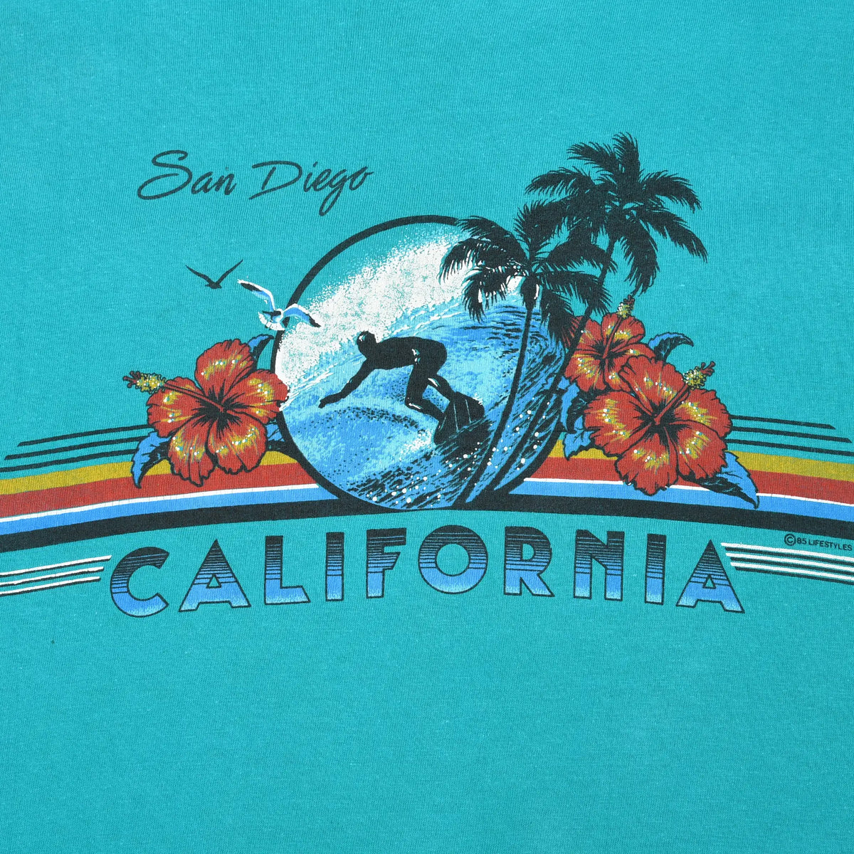 Close-up of San Diego California surf graphic with surfer, wave, palm trees, hibiscus, and stripes