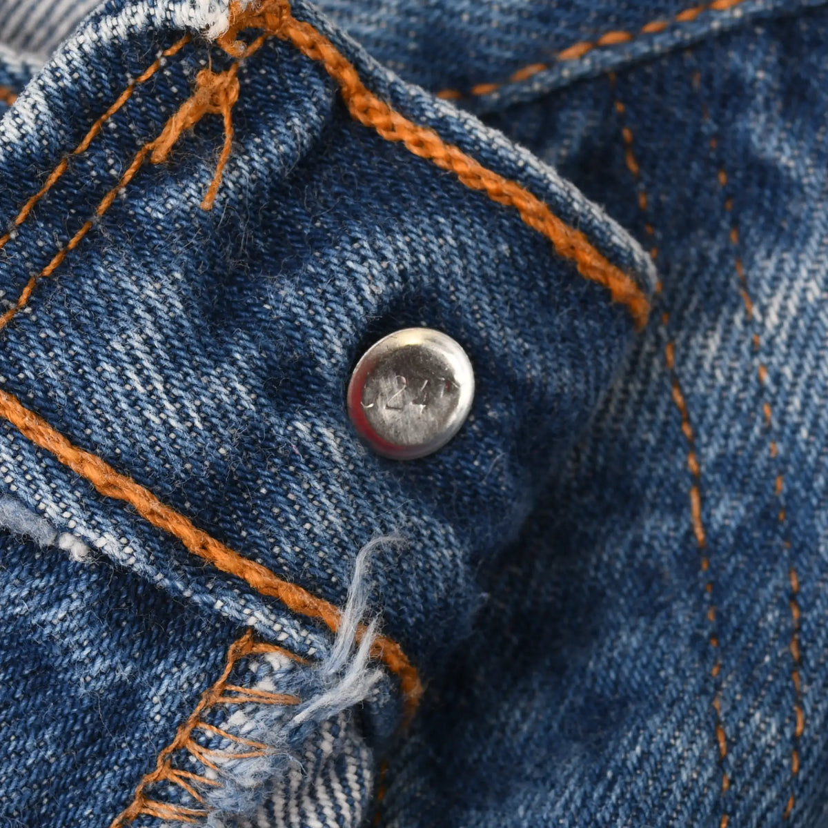Close-up of Levi's jeans waistband button stamped 524 and orange stitching