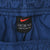 Close-up of black Nike waistband label with red Swoosh and XL size marking