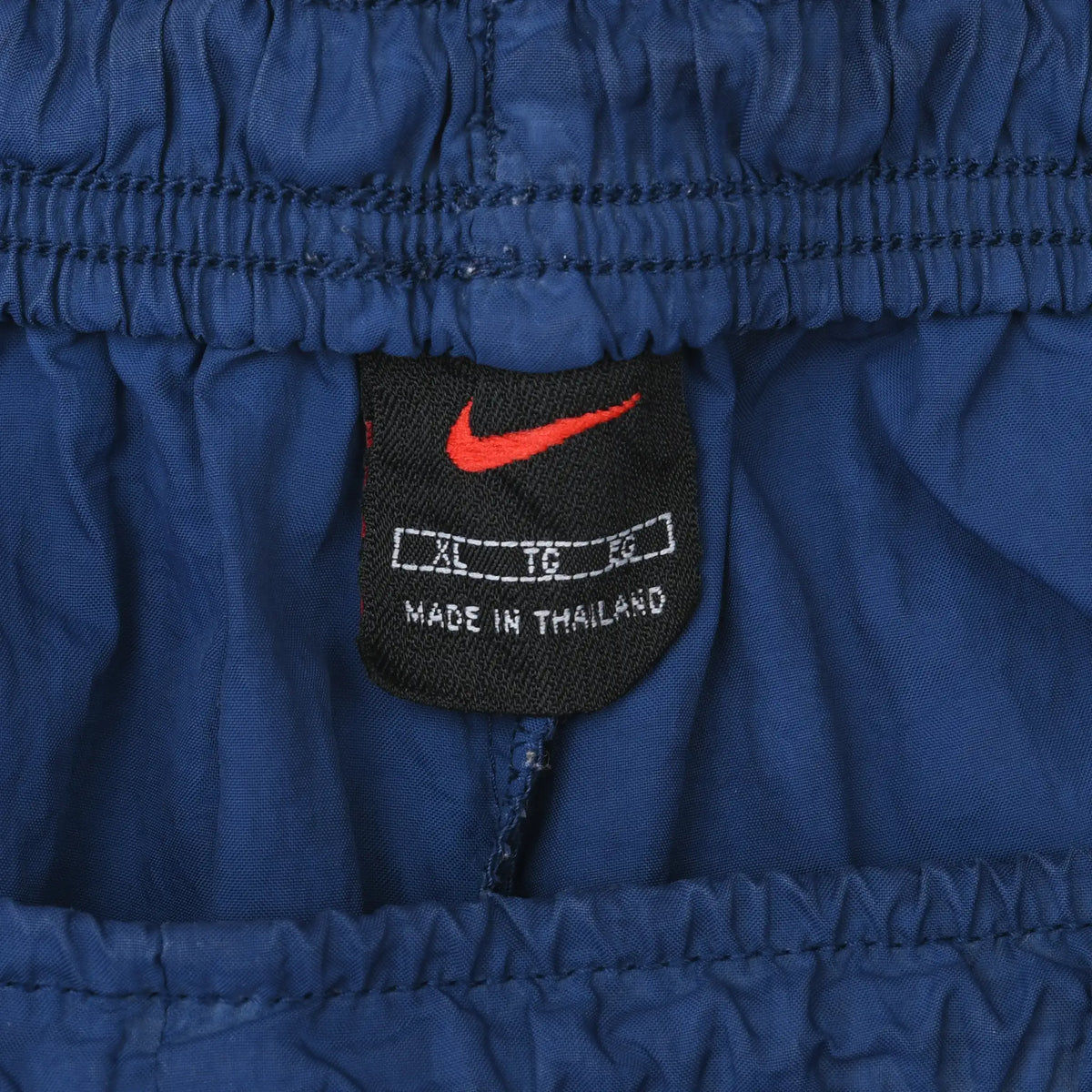 Close-up of black Nike waistband label with red Swoosh and XL size marking