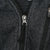 Close-up of dark grey fleece texture and YKK quarter-zip pull
