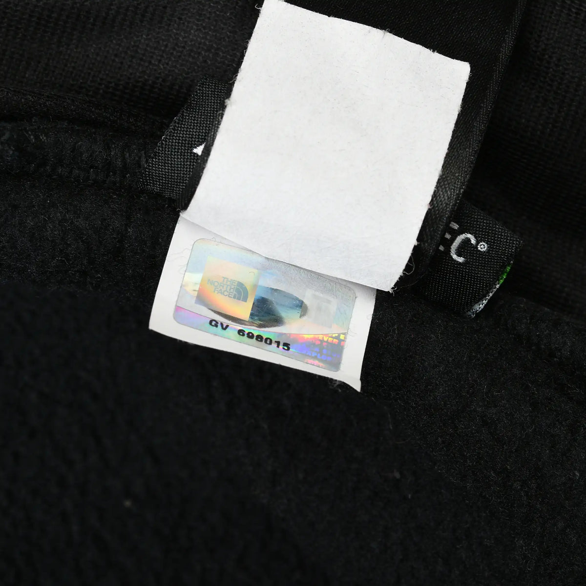 Close-up of The North Face hologram label inside black fleece jacket