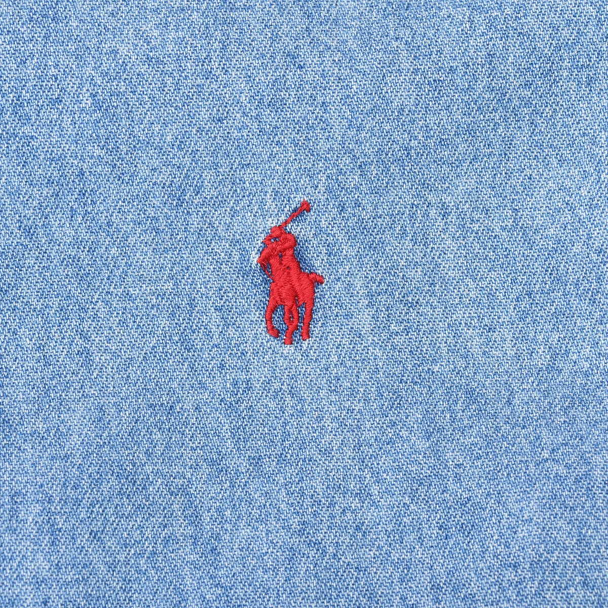 Close-up of red Polo pony embroidery on blue denim shirt chest