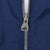 Close-up of silver Adidas logo zipper pull on navy jacket fabric