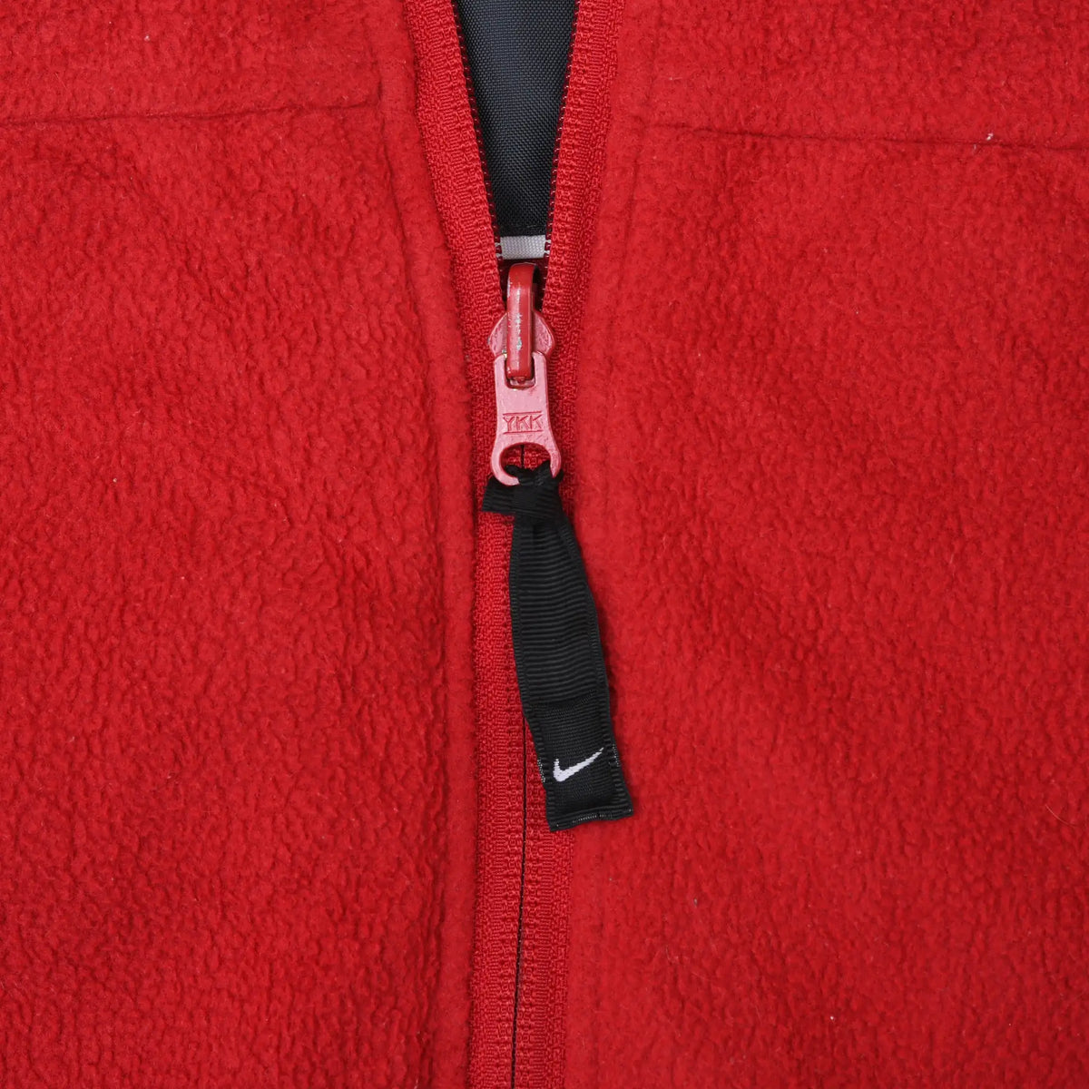 Close-up of red jacket zipper with black Nike Swoosh pull tab