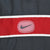 Close-up of Nike Swoosh patch on the red and white chest stripe of the black jacket