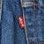 Red Levi's tab beside orange-stitched back pocket on blue denim