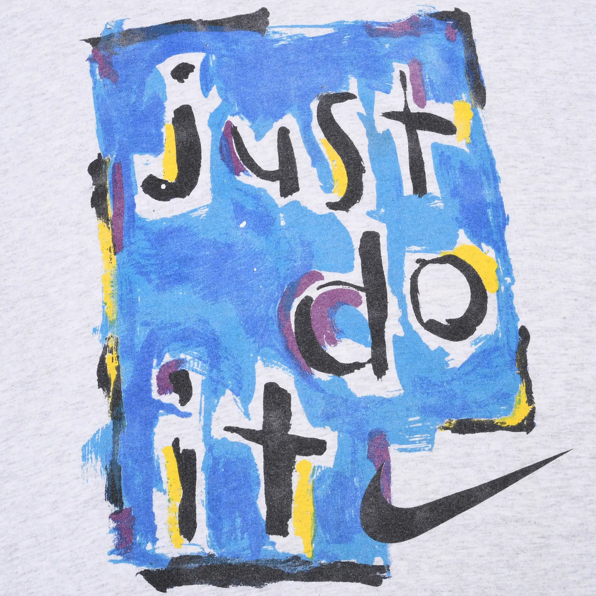 Close-up of blue painted Just Do It graphic with black Nike Swoosh on grey T-shirt