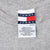 Close-up of Tommy Jeans neck tag with navy, white and red flag logo and care text