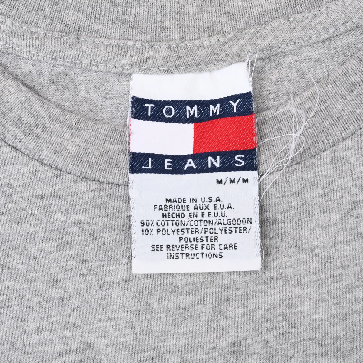 Close-up of Tommy Jeans neck tag with navy, white and red flag logo and care text