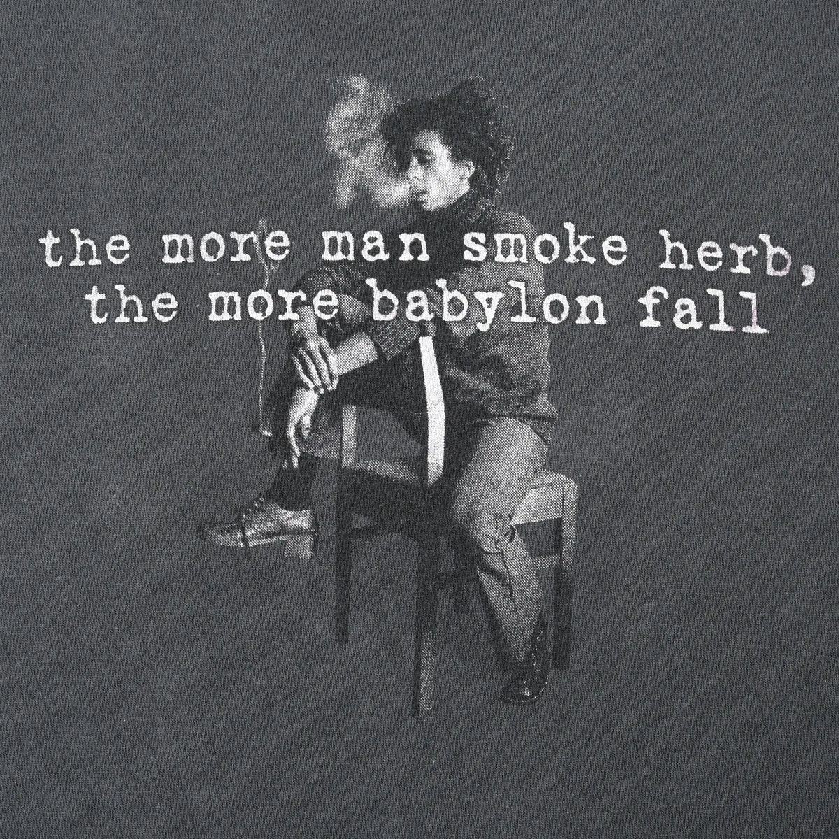 Close-up of back print reading “the more man smoke herb, the more babylon fall” over a portrait