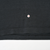 Close-up of black fabric near the bottom hem with a small flaw marked by an arrow