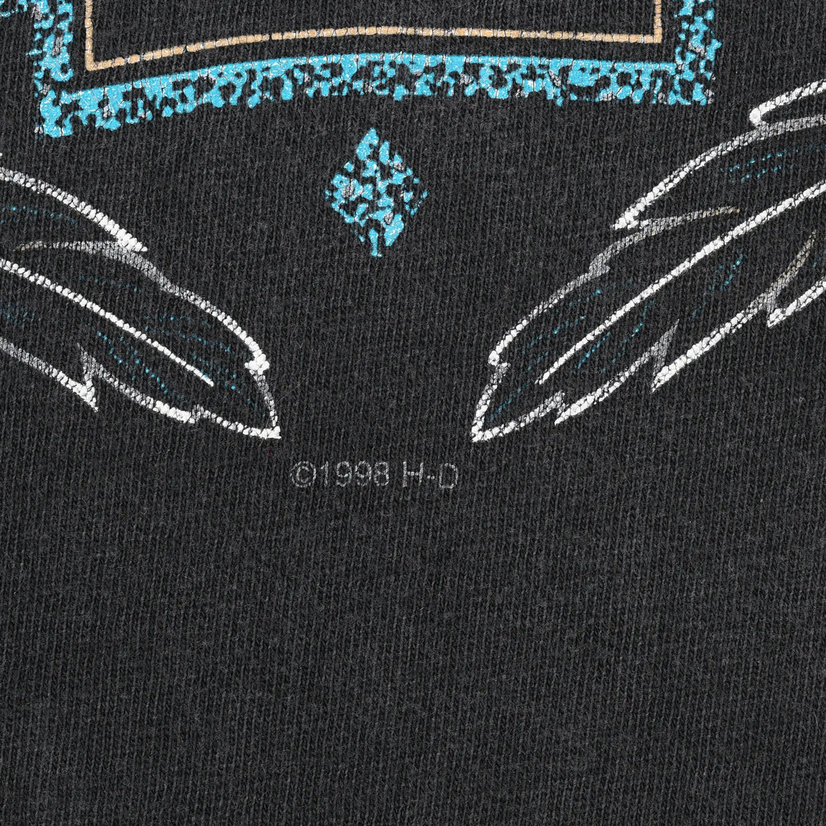 Close-up of feather details and ©1998 H-D text beneath the Harley-Davidson front graphic