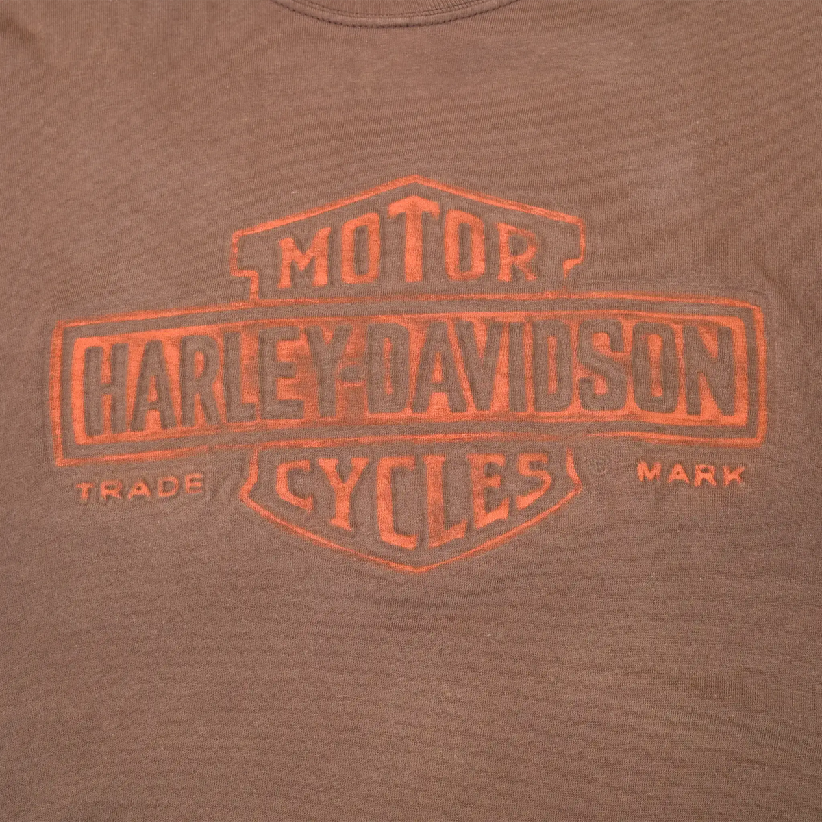 Close-up of orange Harley-Davidson Motor Cycles front print on brown fabric