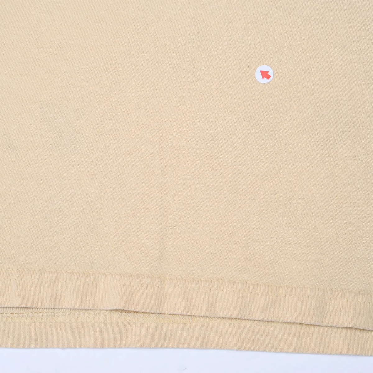 Close-up of tan T-shirt fabric and bottom hem stitching
