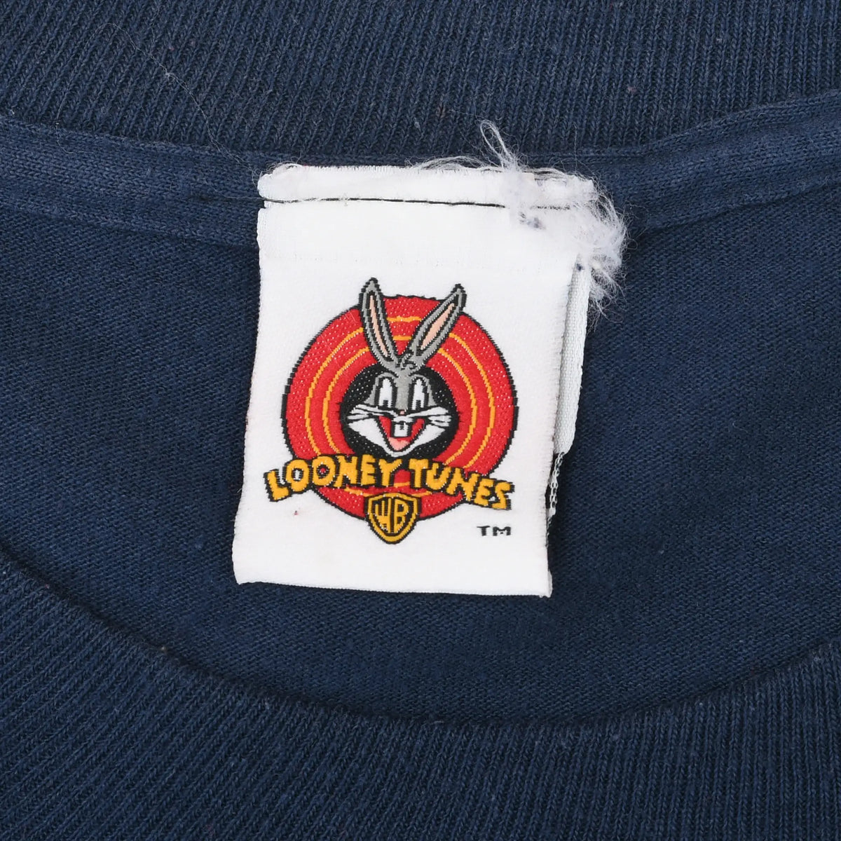 Close-up of Looney Tunes Bugs Bunny neck tag on navy T-shirt