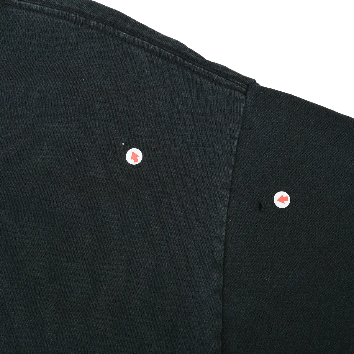 Close-up of two small holes near the T-shirt shoulder seam, marked with arrows