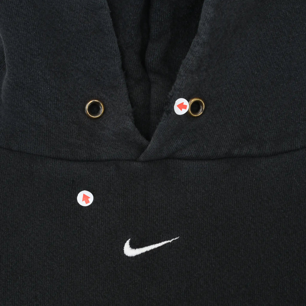 Close-up of hoodie neckline, metal eyelets, and white center Nike Swoosh with marked areas