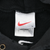 Close-up of white Nike neck tag with red Swoosh and L marking inside black hoodie