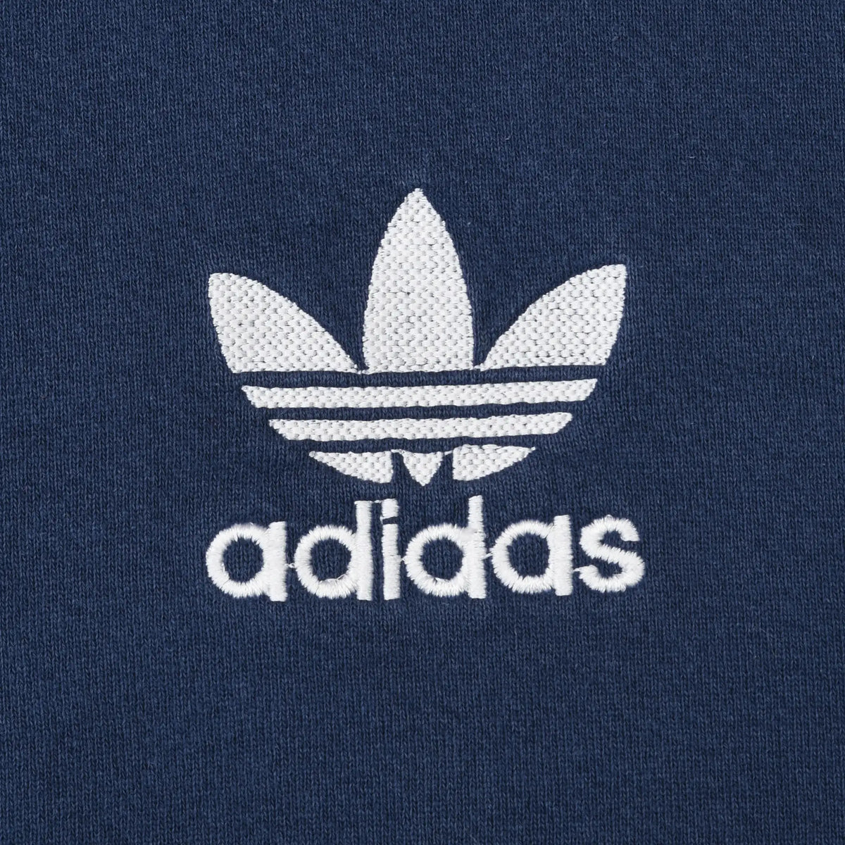 Close-up of white adidas Trefoil logo embroidery on navy blue fabric